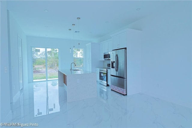 kitchen with a center island with sink, light stone countertops, appliances with stainless steel finishes, decorative light fixtures, and white cabinetry