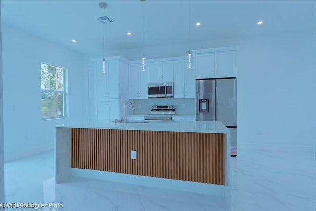 kitchen with a kitchen island with sink, hanging light fixtures, white cabinets, and stainless steel appliances