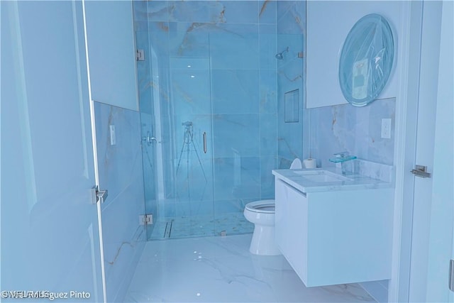 bathroom with vanity, toilet, a shower with door, and tile walls