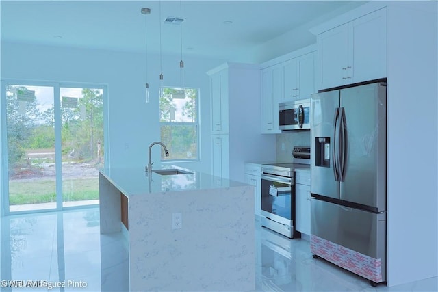 kitchen featuring stainless steel appliances, sink, decorative light fixtures, a center island with sink, and white cabinetry