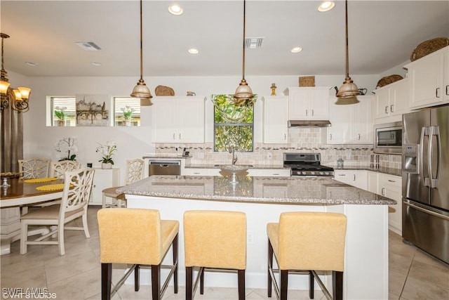 kitchen with stainless steel appliances, a center island, white cabinets, and decorative light fixtures