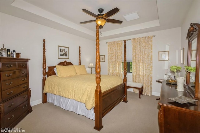 bedroom with light carpet, a tray ceiling, a ceiling fan, and baseboards