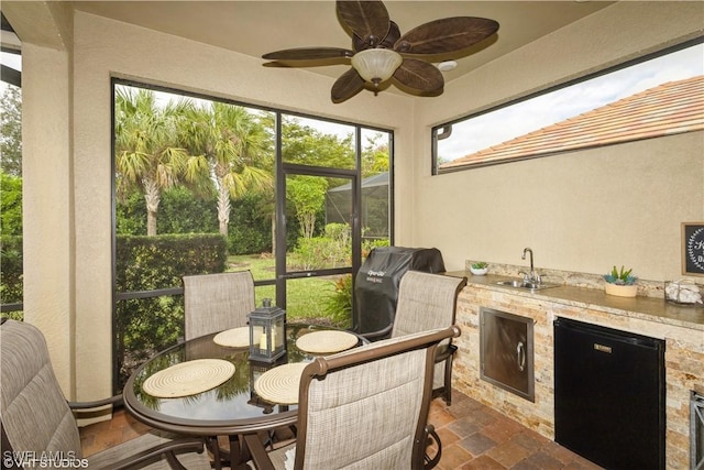 sunroom / solarium featuring a ceiling fan, wet bar, and a sink