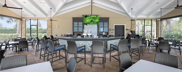 kitchen featuring beam ceiling, dark countertops, a ceiling fan, glass insert cabinets, and tile patterned flooring