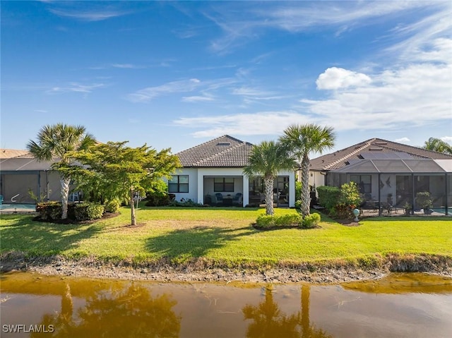 rear view of property featuring a lanai, a yard, and a water view