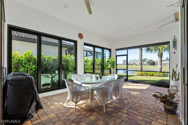 sunroom / solarium with a water view and ceiling fan