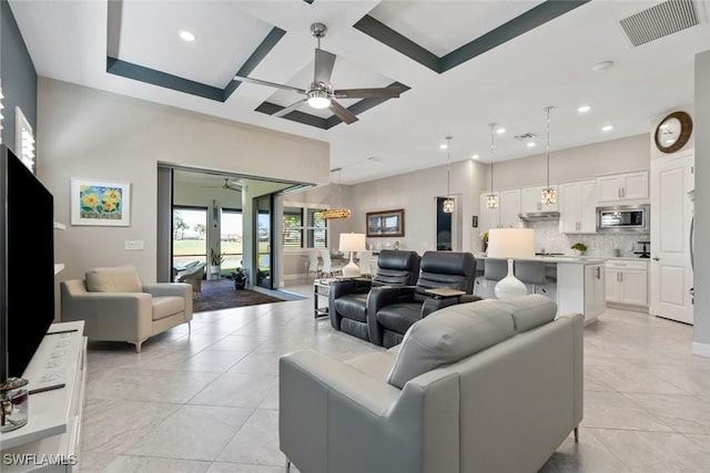 living room featuring ceiling fan, light tile patterned floors, and coffered ceiling