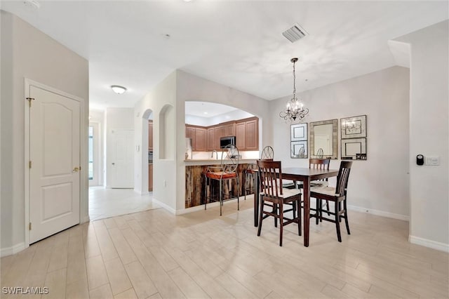 4350 Lazio Way Unit 1102, Fort Myers, FL 33901 - dining area featuring arched walkways, a chandelier, and light wood-style floors