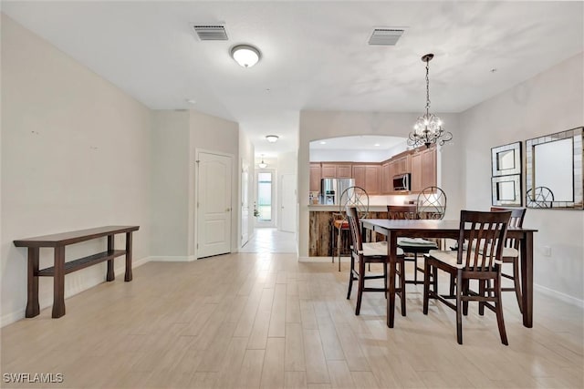 4350 Lazio Way Unit 1102, Fort Myers, FL 33901 - dining area featuring a chandelier, arched walkways, and light wood-style floors