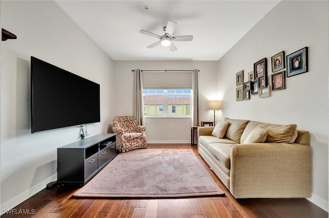 living area featuring baseboards, dark wood-type flooring, and ceiling fan