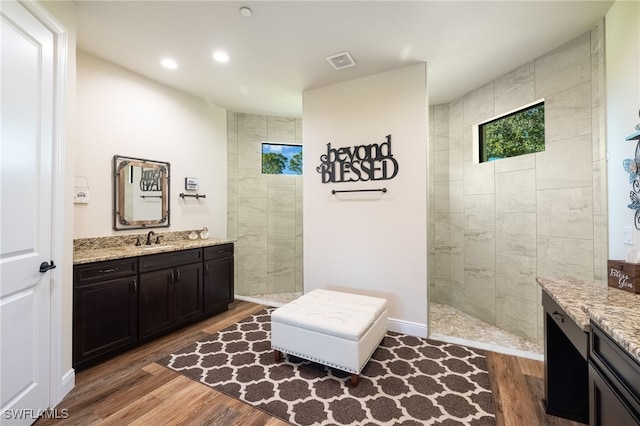 bathroom featuring tiled shower, wood-type flooring, and vanity