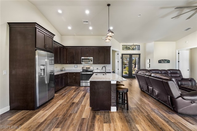 kitchen with sink, light stone counters, a kitchen bar, a center island with sink, and appliances with stainless steel finishes