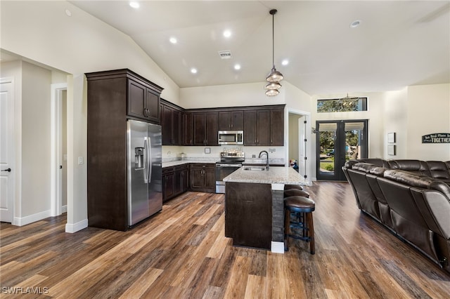 kitchen with light stone countertops, sink, a breakfast bar area, a center island with sink, and appliances with stainless steel finishes