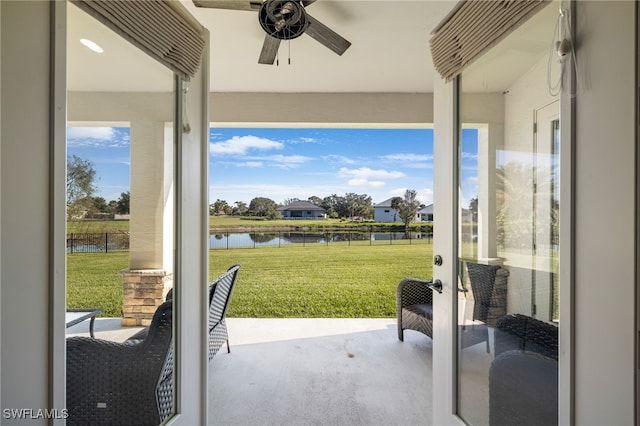 doorway with ceiling fan and a water view