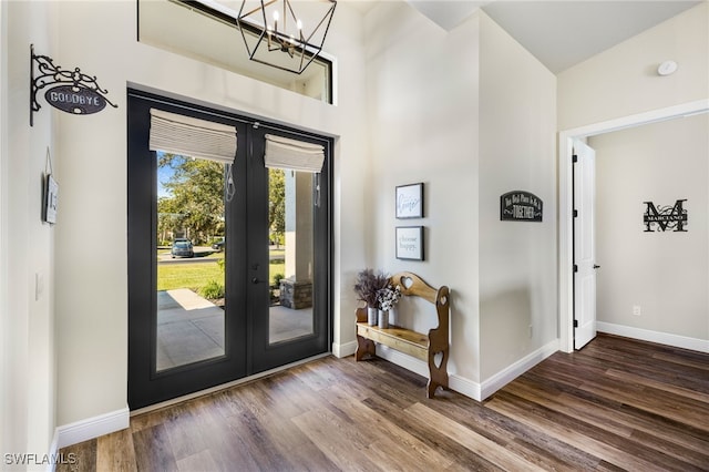 foyer entrance with french doors, dark hardwood / wood-style floors, and a notable chandelier