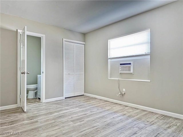 unfurnished bedroom with connected bathroom, light hardwood / wood-style flooring, and cooling unit