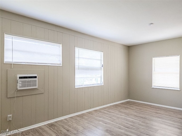 spare room with plenty of natural light, wood walls, light hardwood / wood-style floors, and cooling unit