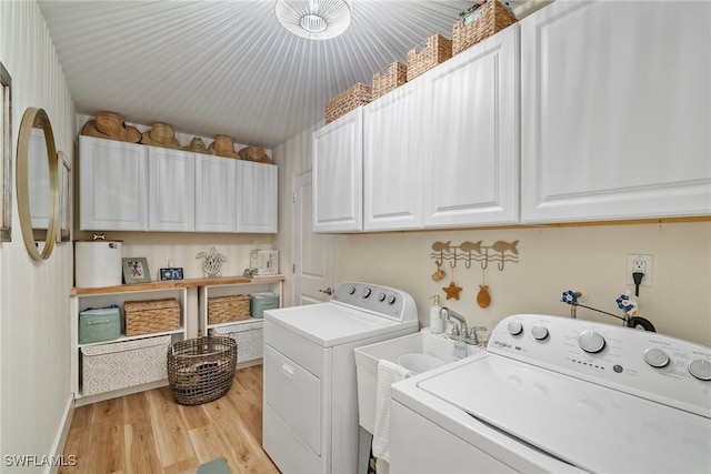 laundry room featuring washer and clothes dryer, light wood-type flooring, and cabinets