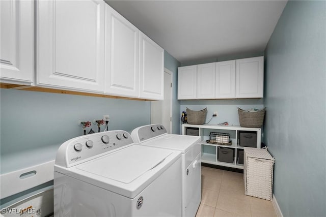 laundry room featuring cabinets, light tile patterned floors, and washing machine and clothes dryer