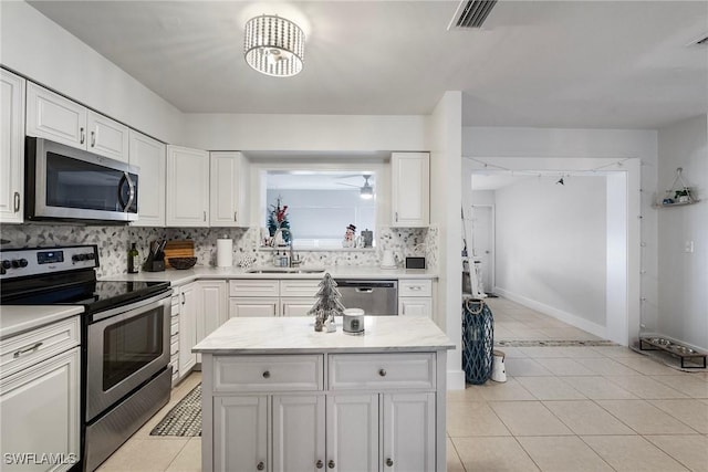 kitchen with light tile patterned floors, appliances with stainless steel finishes, sink, and white cabinetry