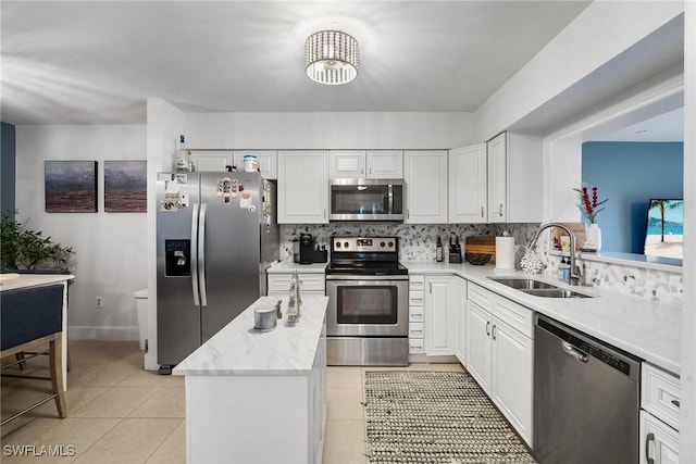 kitchen with white cabinetry, appliances with stainless steel finishes, light tile patterned flooring, a kitchen island, and sink