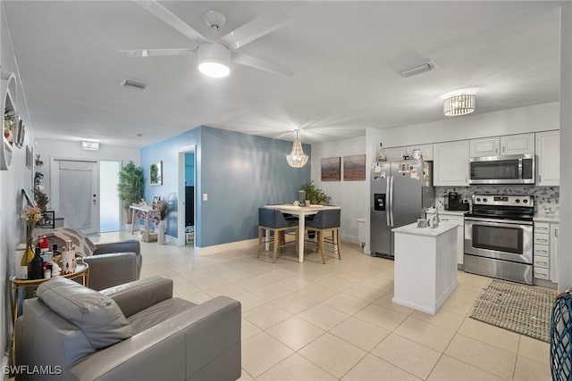 kitchen featuring light tile patterned floors, white cabinetry, appliances with stainless steel finishes, tasteful backsplash, and pendant lighting