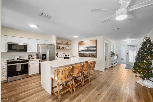 kitchen with a center island, a kitchen bar, white cabinetry, stainless steel appliances, and backsplash