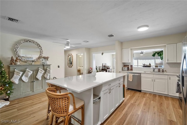 kitchen with white cabinetry, sink, dishwasher, and a center island