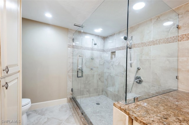 bathroom featuring toilet and a shower with door