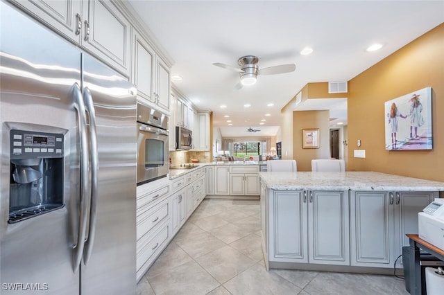 kitchen featuring white cabinets, ceiling fan, kitchen peninsula, light stone countertops, and appliances with stainless steel finishes