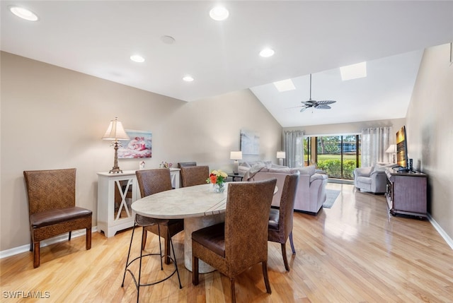 dining room featuring ceiling fan, vaulted ceiling with skylight, and light wood-type flooring