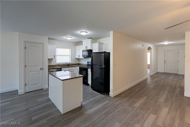 kitchen featuring a center island, black appliances, sink, dark hardwood / wood-style flooring, and white cabinetry