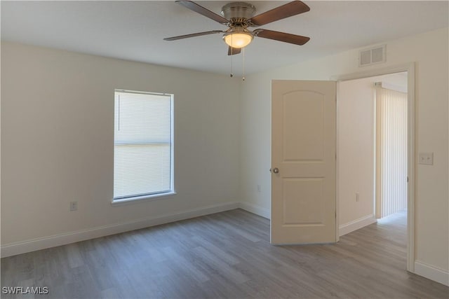 spare room featuring a wealth of natural light, light hardwood / wood-style flooring, and ceiling fan