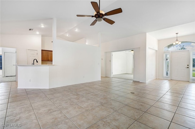 unfurnished living room with sink, high vaulted ceiling, ceiling fan with notable chandelier, and light tile patterned floors