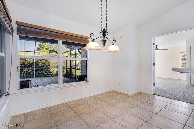 unfurnished dining area with ceiling fan with notable chandelier and light tile patterned floors