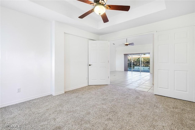 carpeted spare room featuring ceiling fan and a tray ceiling