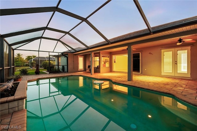 pool at dusk featuring ceiling fan, a lanai, french doors, and a patio area