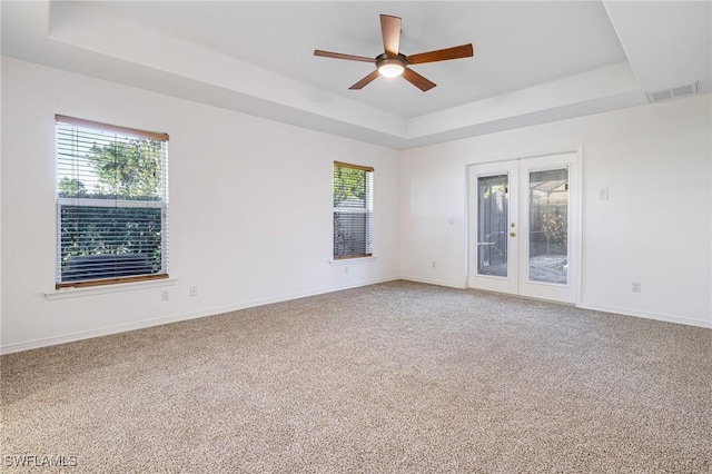 carpeted spare room with french doors, ceiling fan, and a tray ceiling