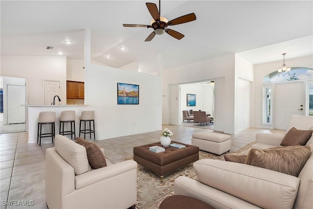 living room featuring ceiling fan with notable chandelier, high vaulted ceiling, light tile patterned flooring, and sink