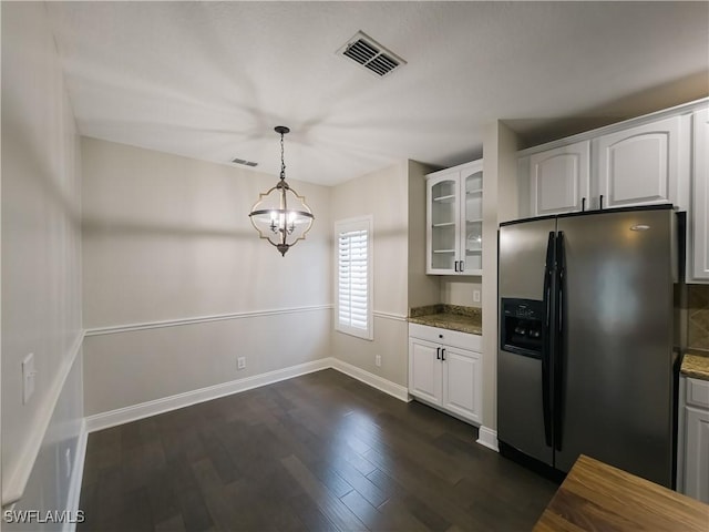 kitchen featuring stainless steel refrigerator with ice dispenser, white cabinetry, and dark stone countertops