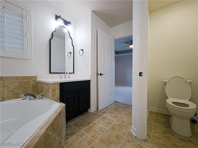 bathroom featuring vanity, a relaxing tiled tub, toilet, and ceiling fan