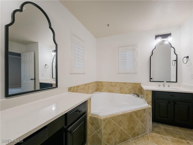 bathroom with tile patterned floors, tiled tub, and vanity