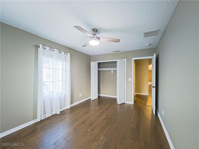 unfurnished bedroom with a textured ceiling, ceiling fan, a closet, and dark hardwood / wood-style floors