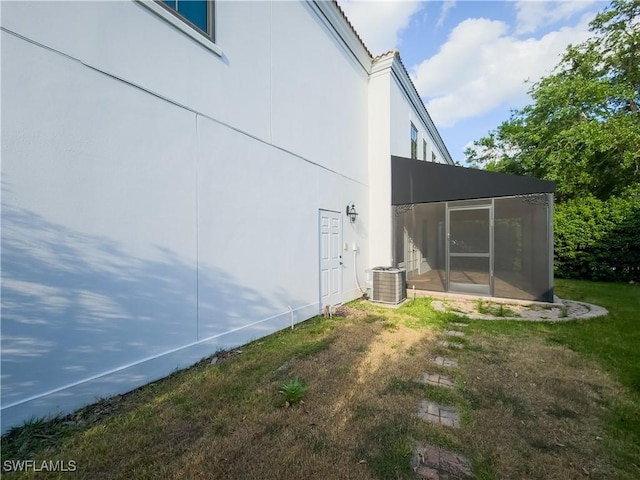 view of home's exterior featuring central AC, a sunroom, and a yard