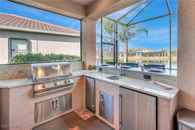 view of patio / terrace featuring a water view, area for grilling, an outdoor kitchen, and sink