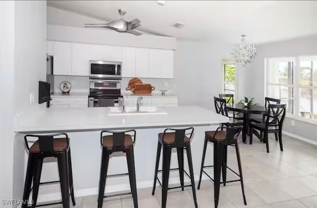 kitchen featuring range, white cabinets, sink, kitchen peninsula, and a breakfast bar area