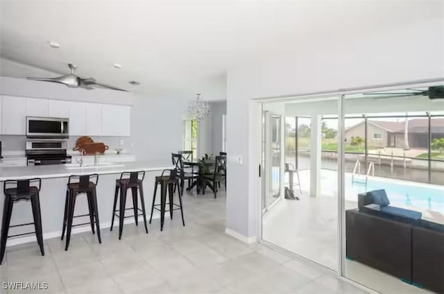 kitchen with ceiling fan, a breakfast bar, white cabinets, and range