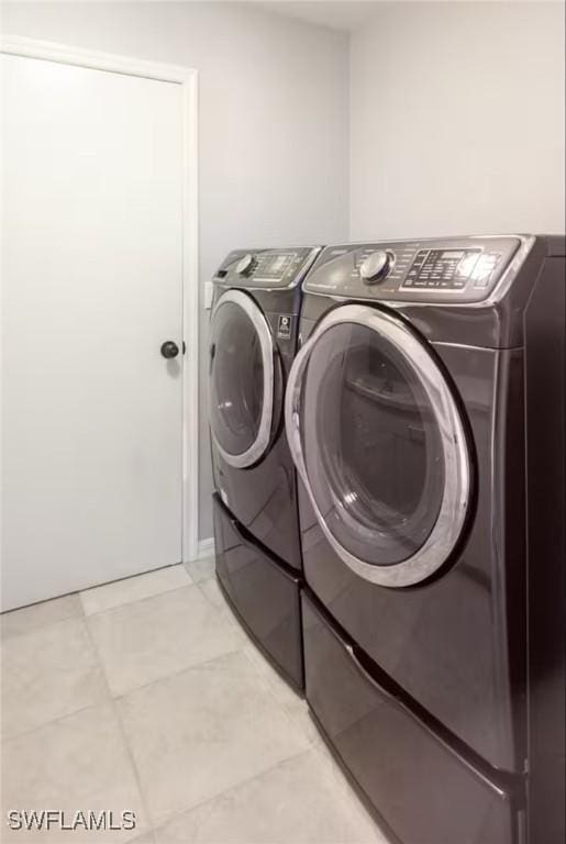 laundry area with light tile patterned floors and washing machine and dryer