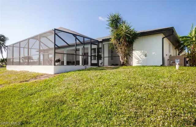 rear view of property featuring a yard and glass enclosure