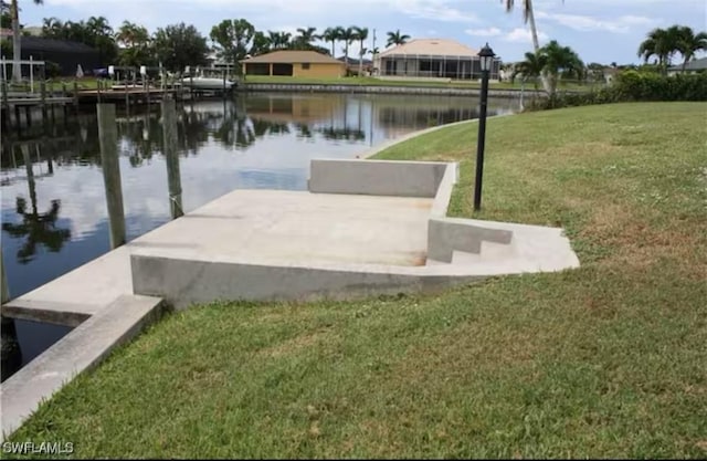 dock area with a lawn and a water view